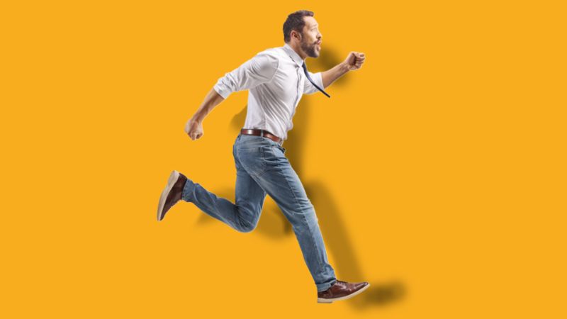 Homme portant une cravate et courant vers la droite, sur un fond orange.